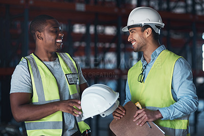 Buy stock photo Shot of two young contractors standing in the warehouse together and having a discussion