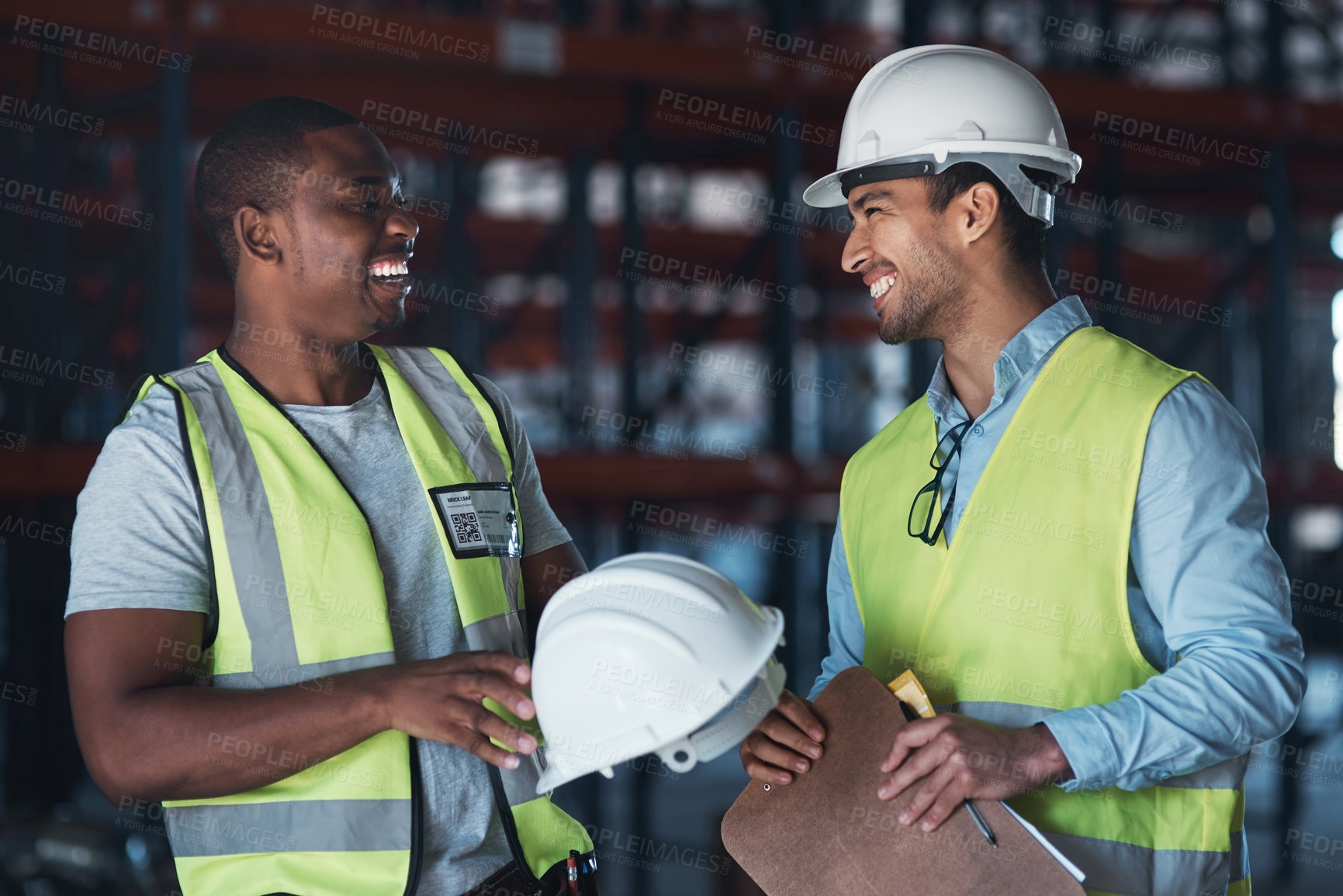 Buy stock photo Shot of two young contractors standing in the warehouse together and having a discussion