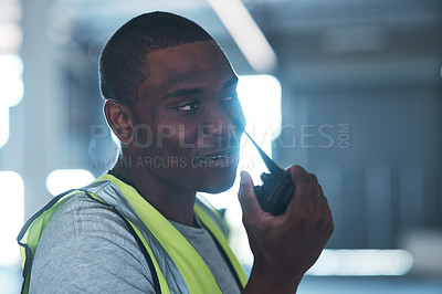 Buy stock photo Shot of a handsome young contractor standing alone in the warehouse and using a walkie talkie