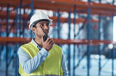 Buy stock photo Shot of a handsome young contractor standing alone in the warehouse and using a walkie talkie