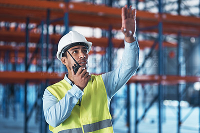 Buy stock photo Shot of a handsome young contractor standing alone in the warehouse and using a walkie talkie