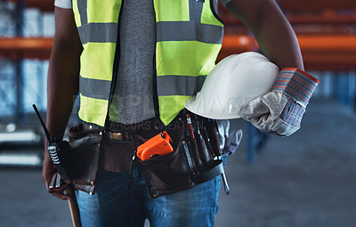 Buy stock photo Cropped shot of an unrecognizable contractor standing alone in the warehouse and holding his hardhat