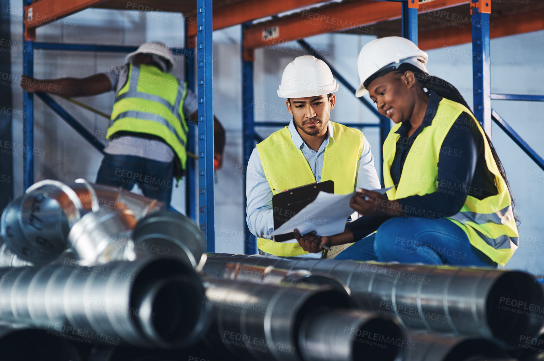 Buy stock photo Shot of two young contractors crouched down in the warehouse and having a discussion while doing a stock-take