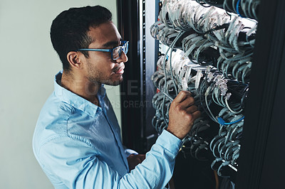 Buy stock photo Shot of a handsome young technician standing alone and looking at the mainframe