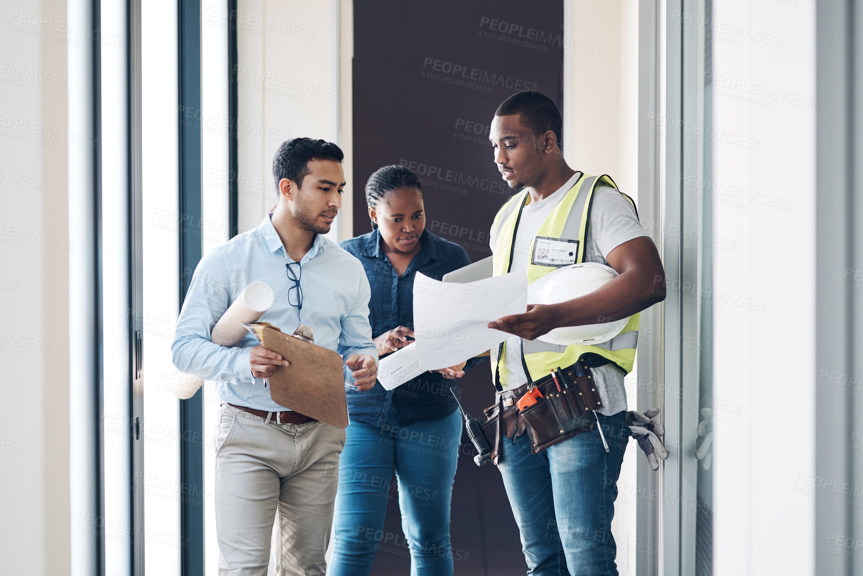 Buy stock photo Shot of a group of architects walking together and having a discussion about the room before they renovate