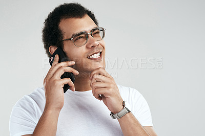 Buy stock photo Shot of a handsome young man talking on his cellphone while standing against a grey background
