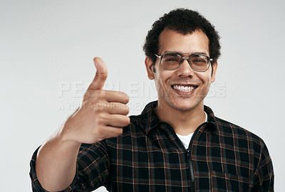 Buy stock photo Shot of a handsome young man showing thumbs up while standing against a grey background