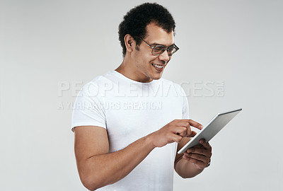 Buy stock photo Shot of a man using a digital tablet while standing against a grey background
