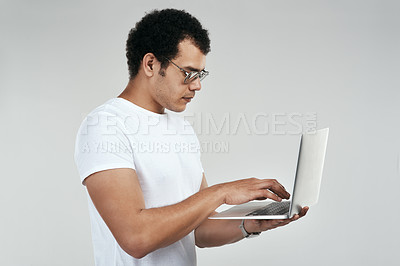 Buy stock photo Shot of a man using a laptop while standing against a grey background