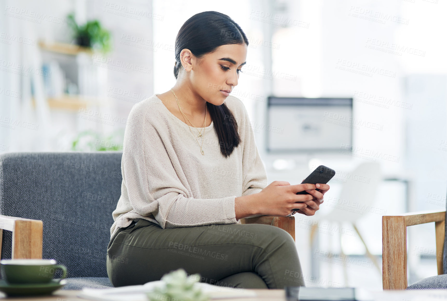 Buy stock photo Shot of a young businesswoman using a cellphone in an office