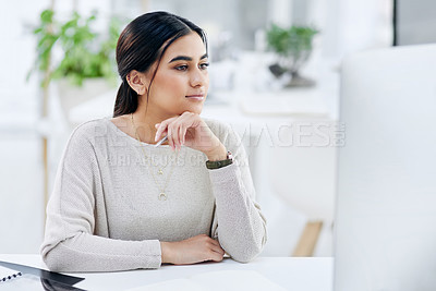 Buy stock photo Shot of a young businesswoman looking thoughtful while working on a computer in an office