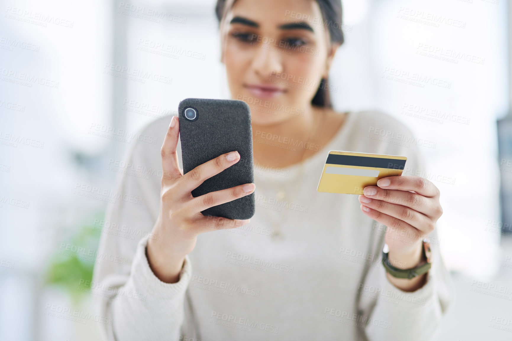 Buy stock photo Shot of a young businesswoman using a cellphone and credit card in an office