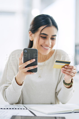 Buy stock photo Shot of a young businesswoman using a cellphone and credit card in an office