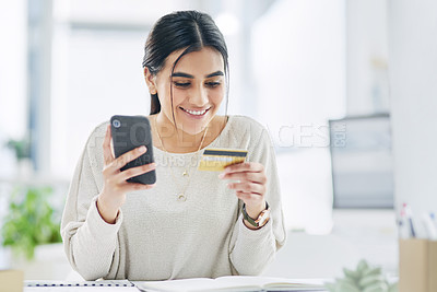 Buy stock photo Shot of a young businesswoman using a cellphone and credit card in an office