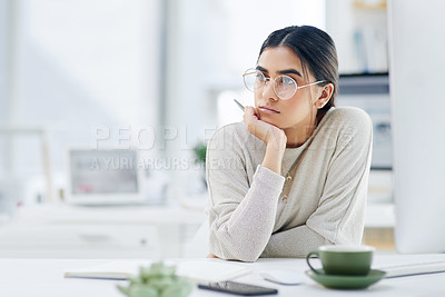 Buy stock photo Shot of a young businesswoman looking thoughtful while working in an office