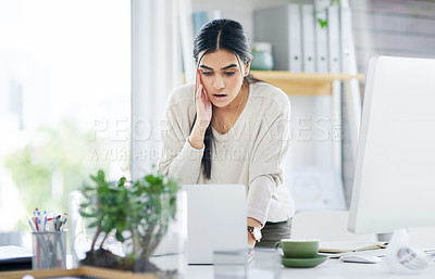 Buy stock photo Shot of a young businesswoman looking shocked while using a laptop in an office