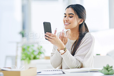 Buy stock photo Shot of a young businesswoman applying lipstick while using her cellphone as a mirror in an office
