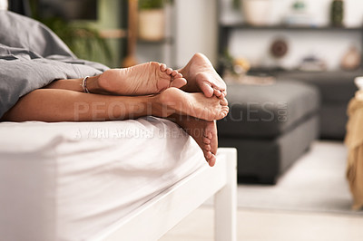 Buy stock photo Shot of a couple’s feet poking out from under the bed sheets