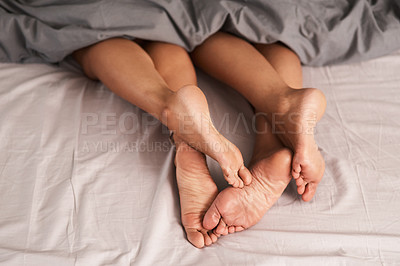 Buy stock photo Shot of a couple’s feet poking out from under the bed sheets