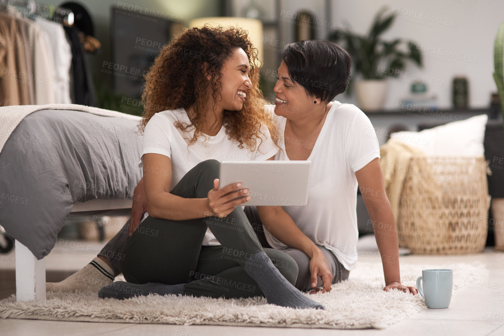 Buy stock photo Shot of a young lesbian couple using a tablet while relaxing in their bedroom