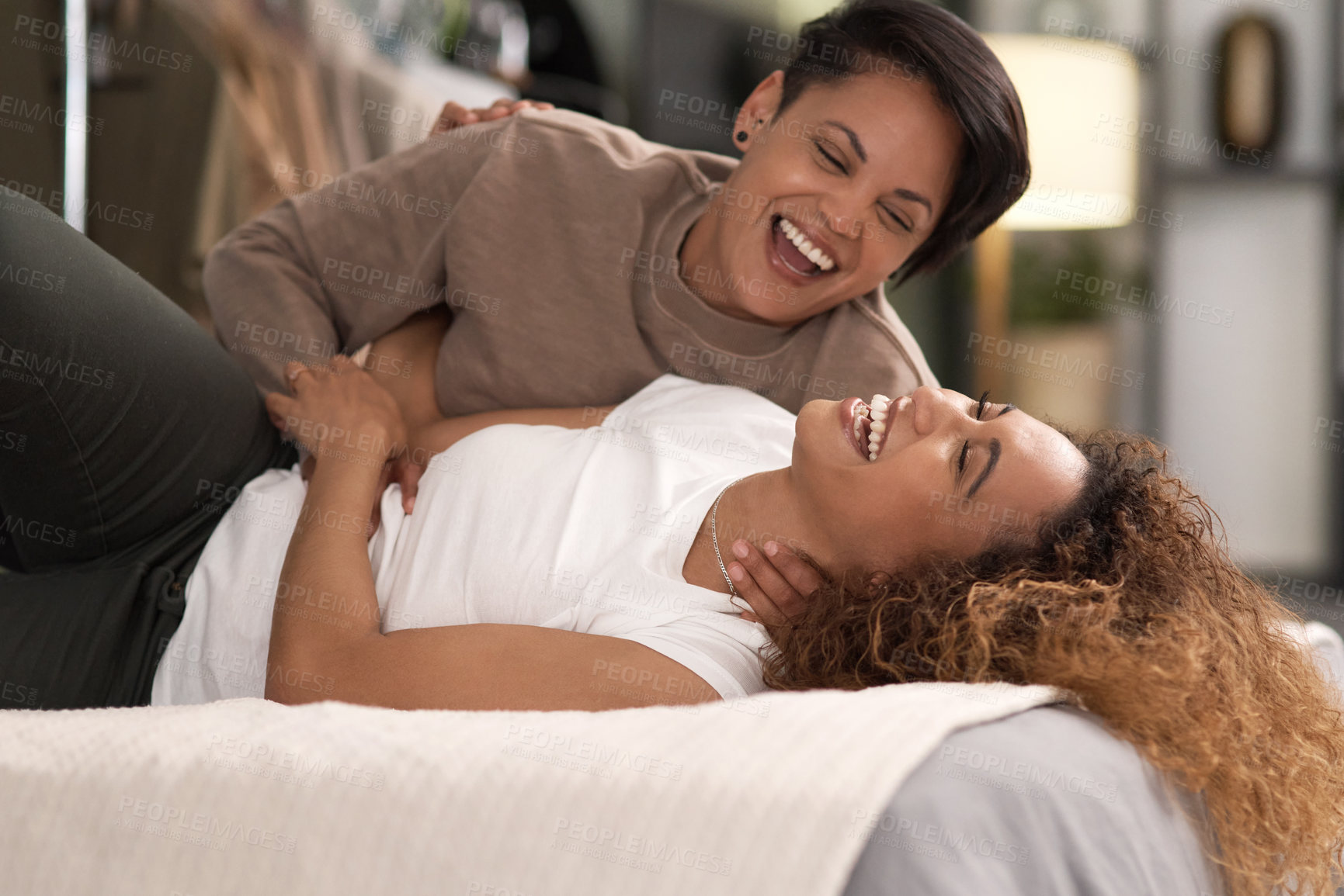 Buy stock photo Shot of a young lesbian couple relaxing in their bedroom at home