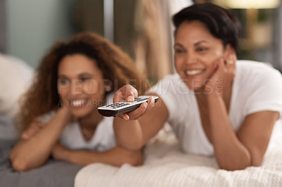 Buy stock photo Shot of a young lesbian couple using a tablet while relaxing in their lounge at home