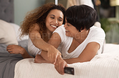 Buy stock photo Shot of a young lesbian couple using a tablet while relaxing in their lounge at home