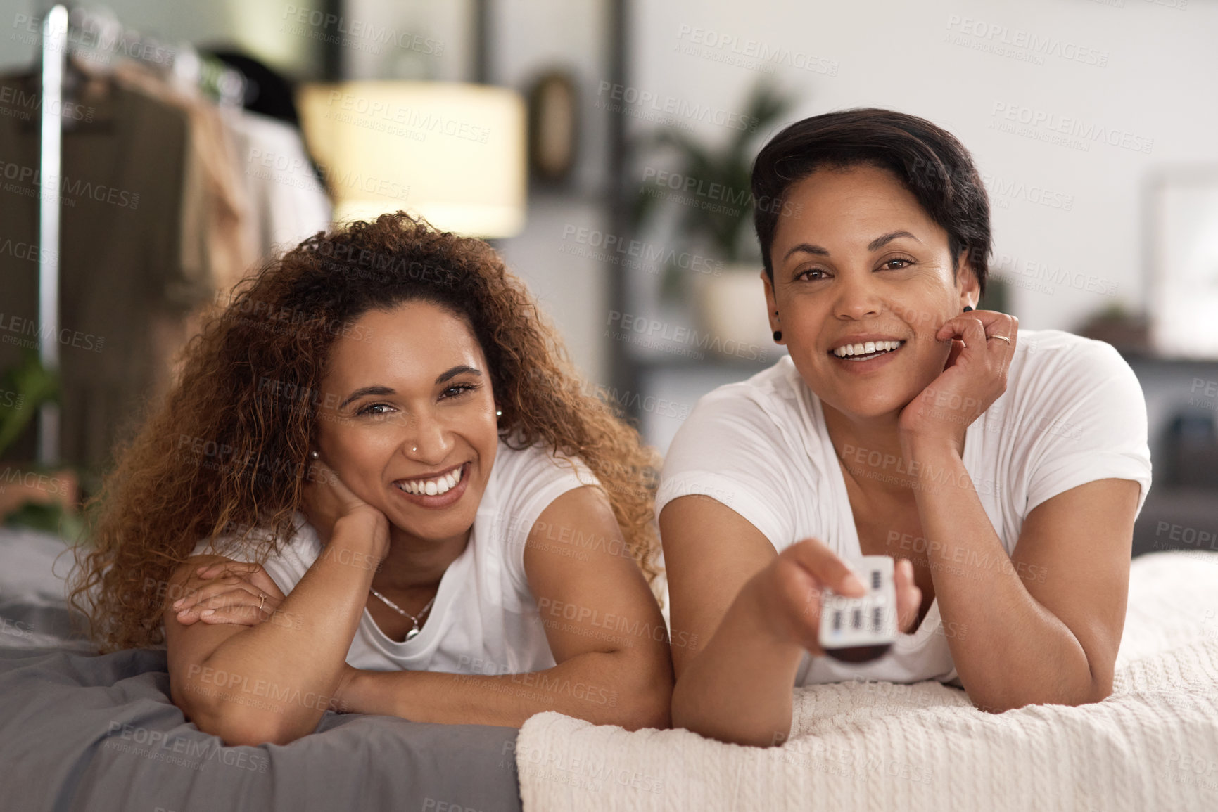 Buy stock photo Shot of a young lesbian couple using a tablet while relaxing in their lounge at home