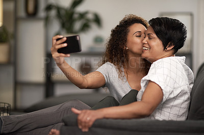 Buy stock photo Shot of a lesbian couple taking a selfie of the couch at home