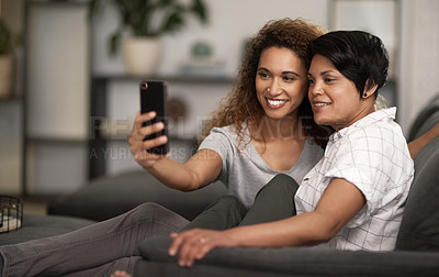 Buy stock photo Shot of a lesbian couple taking a selfie of the couch at home