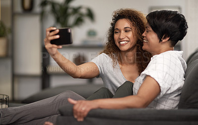 Buy stock photo Shot of a lesbian couple taking a selfie of the couch at home