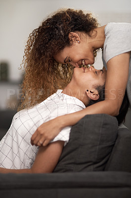 Buy stock photo Shot of an affectionate couple sharing a kiss at home