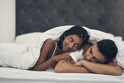 Buy stock photo Shot of a young couple laying in bed at home