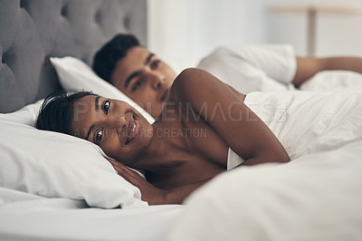 Buy stock photo Shot of a young couple laying in bed at home