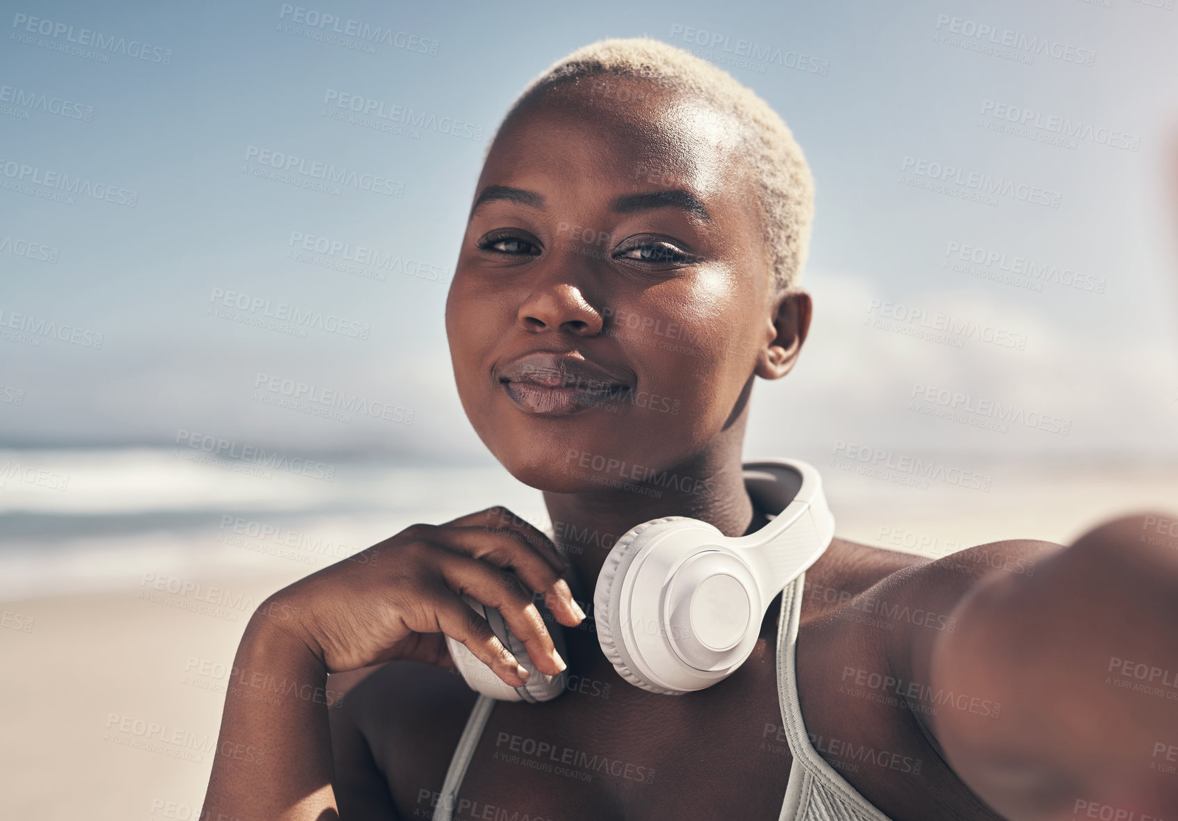 Buy stock photo Shot of a sporty young woman posing with headphones around her neck