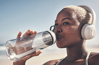 Buy stock photo Shot of a sporty young woman drinking water while out for a workout