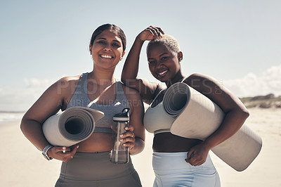 Buy stock photo Shot of two young women holding their yoga mats while  on the beach