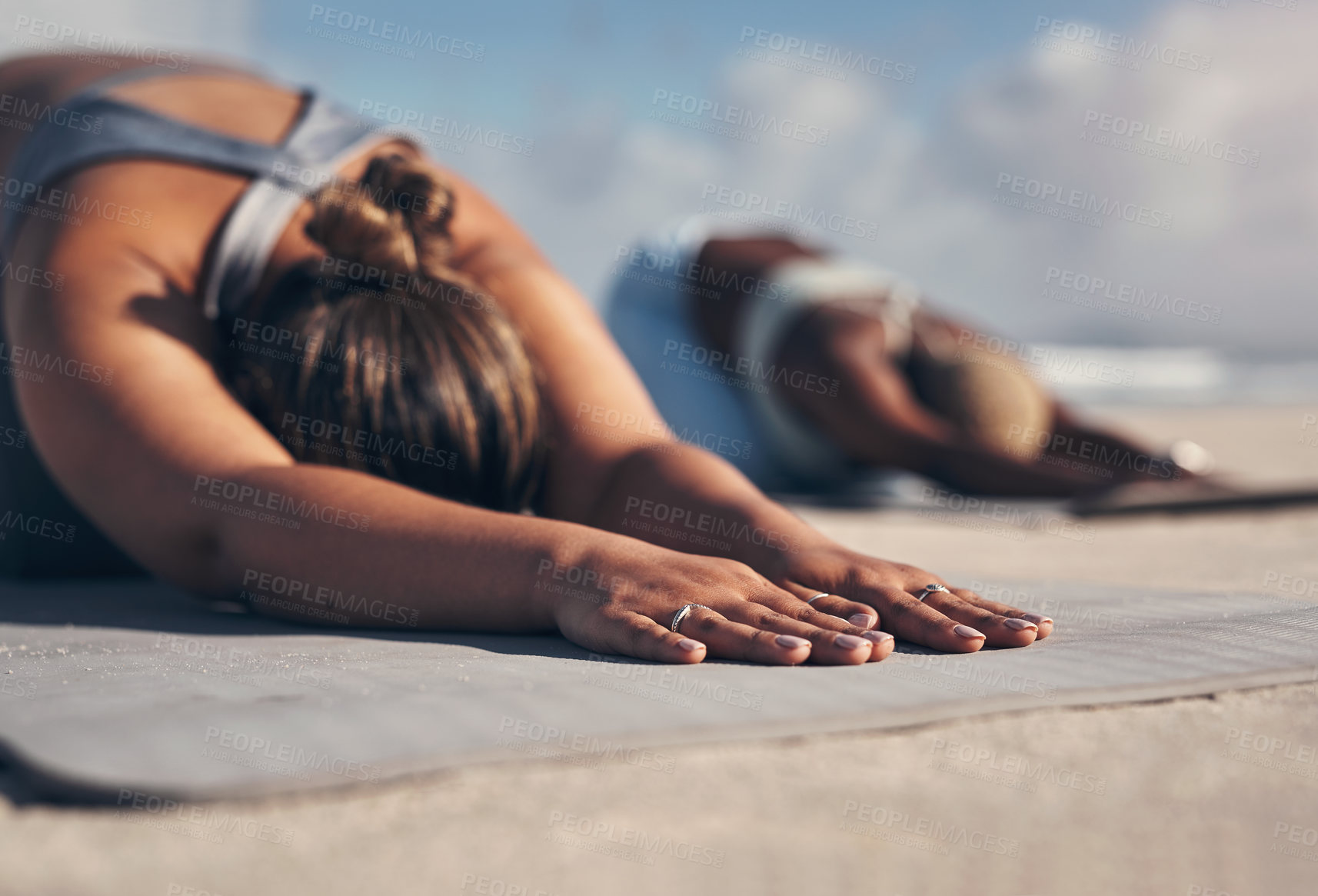 Buy stock photo Shot of two young women practicing yoga on the beach