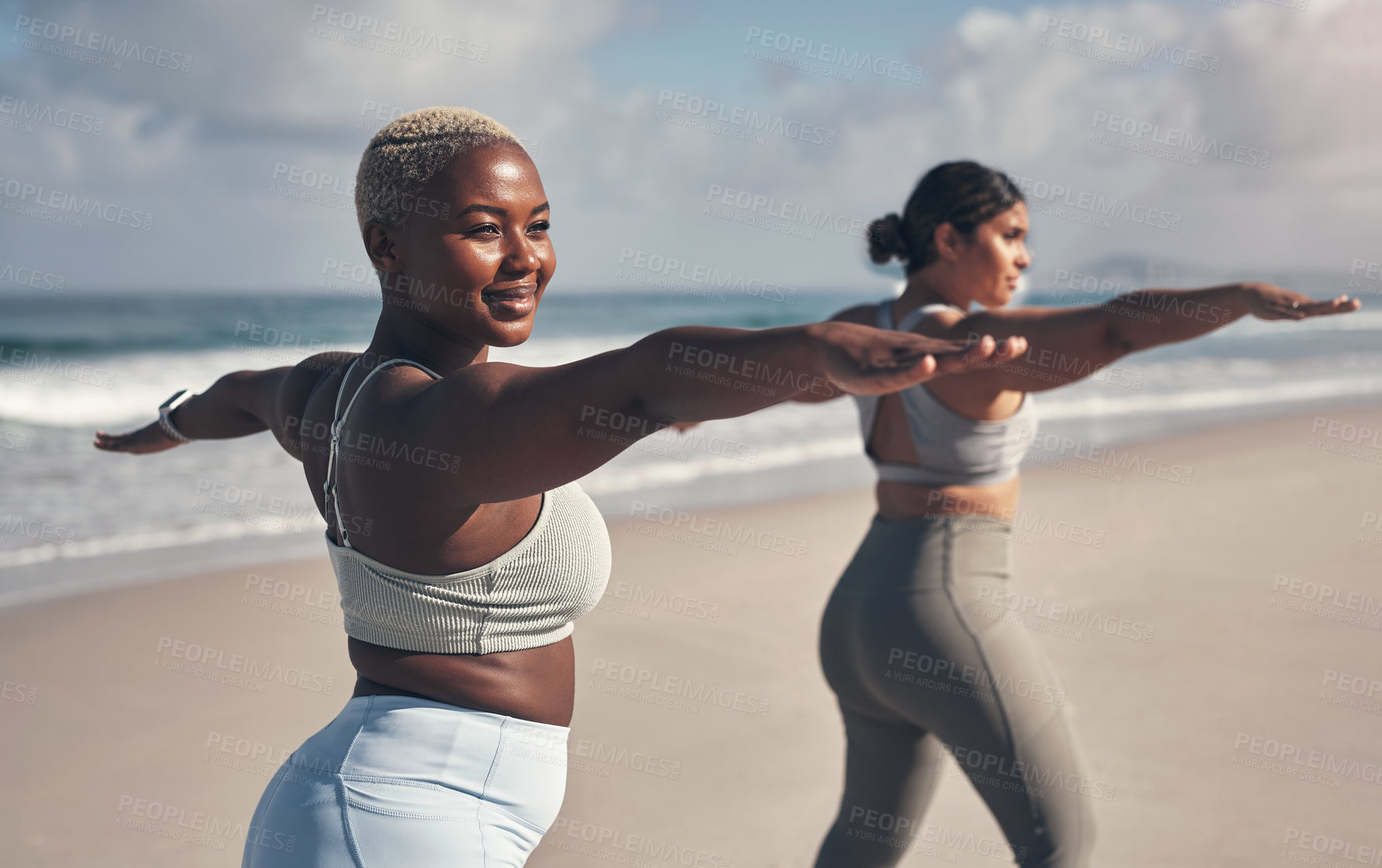 Buy stock photo Shot of two young women practicing yoga on the beach