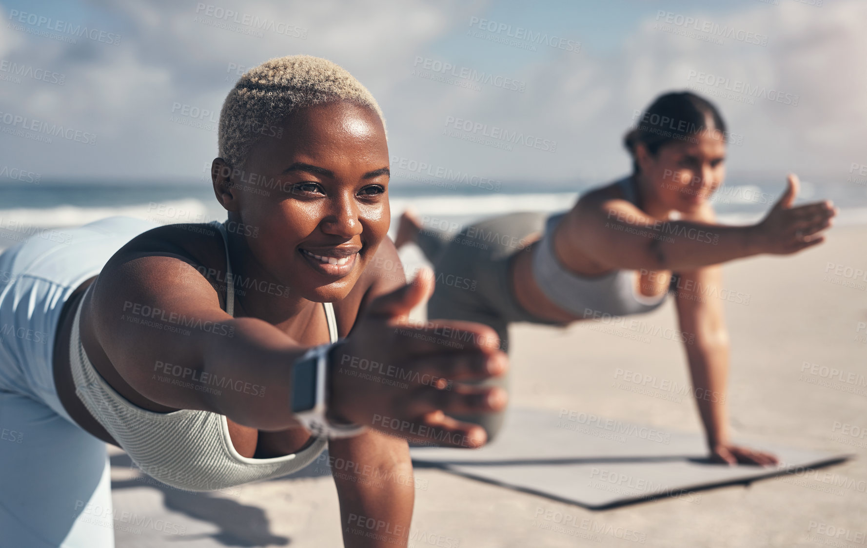 Buy stock photo Shot of two young women practicing yoga on the beach