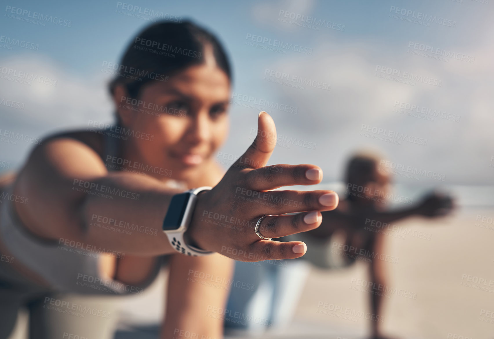 Buy stock photo Shot of a young woman wearing a smartwatch while practicing yoga at the beach