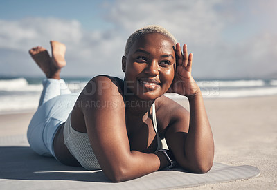 Buy stock photo Shot of a sporty young woman lying on her yoga mat at the beach