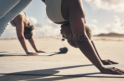 Buy stock photo Shot of two young women practicing yoga on the beach