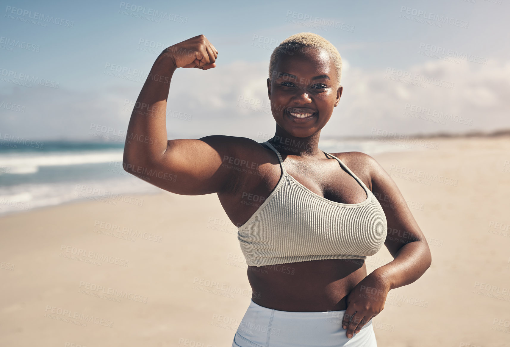 Buy stock photo Shot of a young woman flexing while out for a workout on the beach