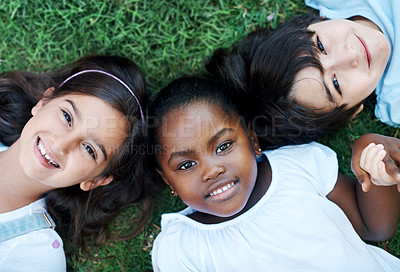 Buy stock photo Shot of three adorable kids lying together on the lawn