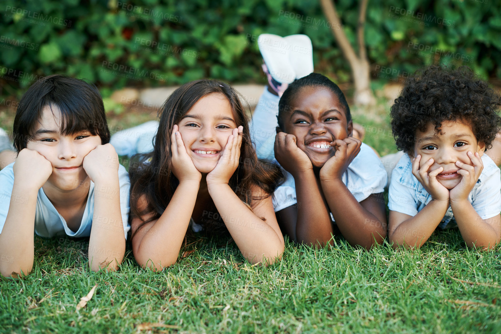 Buy stock photo Shot of four adorable kids lying together on the lawn