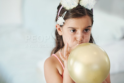 Buy stock photo Shot of an adorable little girl blowing up a balloon at her birthday party