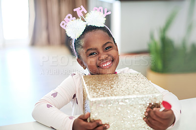 Buy stock photo Shot of a little girl holding on to a gift box on her birthday