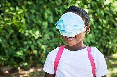 Buy stock photo Shot of a little girl covering her eyes with a mask in nature