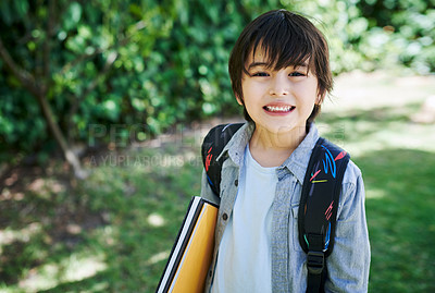 Buy stock photo Shot of a little boy wearing a backpack while carrying books in nature